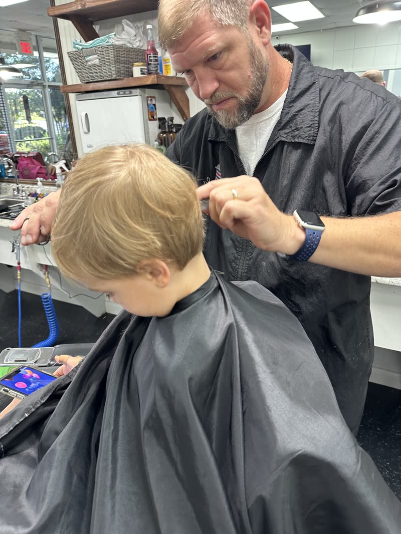 A young client getting a haircut, cape on.