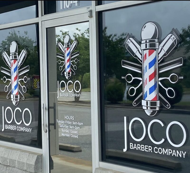 The JoCo Barber Company decal on the front window, a pole either side.