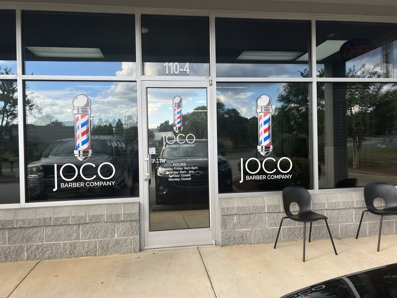 Two barber poles painted across the front windows of Suite 104.