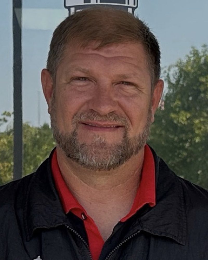 Tracy, owner of JoCo Barber Company, in a red polo and black shop jacket.